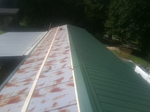 Old rusted panels beside newly installed green metal roofing — Wind Damage Roof Repair by Roofing Brothers in Mapleton